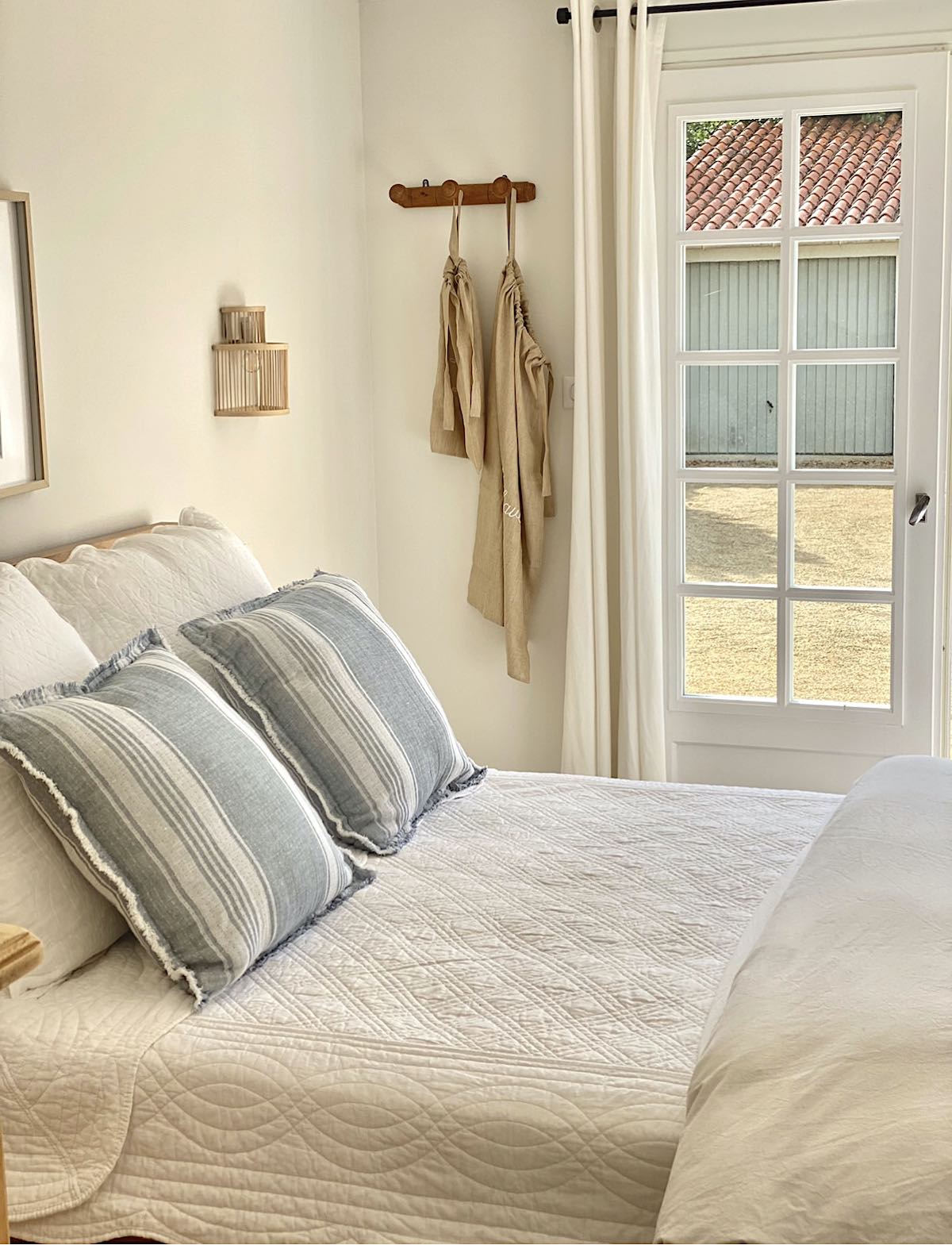 Un lit blanc avec des oreillers bleus et blancs avec des portes françaises à la Maison Coli
