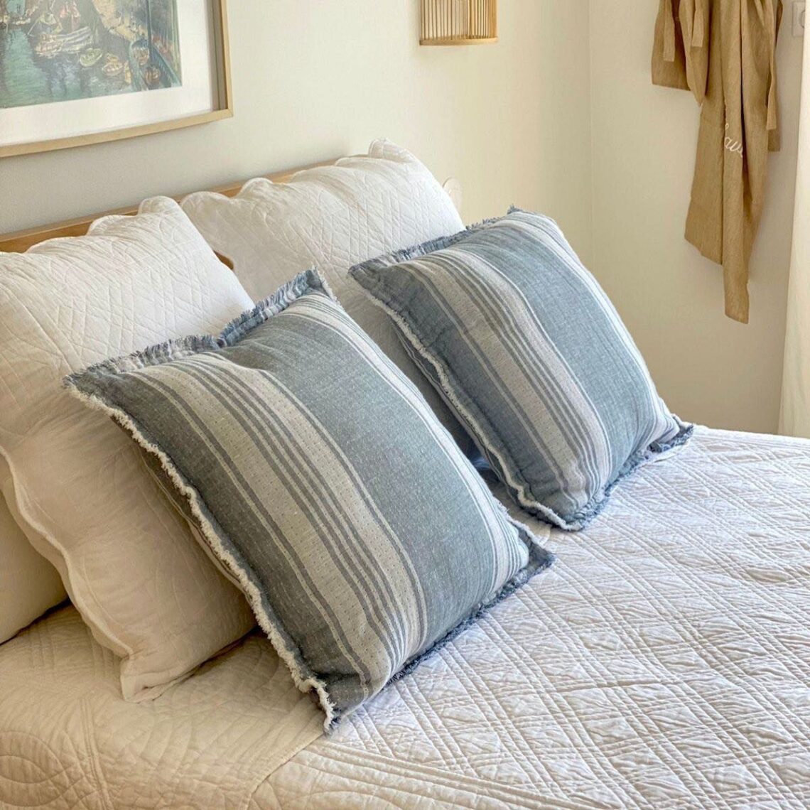 White Bed with Blue and white striped pillows at Maison Coli